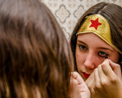 Una ragazza vestita da eroina che si trucca allo specchio