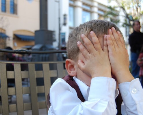 Bambino che si vergogna con mani agli occhi